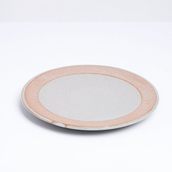 A mino-yaki earthenware small plate, designed by Angle and made in Japan, featuring a central circle of glossy grey glaze and a matching line of grey on its outer rim. An exposed, unglazed clay border of the plate showcases the speckled texture of the raw orange clay. Available at NiMi Projects UK.