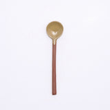 A mino-yaki earthenware tea spoon made in Japan by Angle and available at NiMi Projects UK. Its handle is left as exposed orange clay, while its head has been dipped in a glossy yello glaze.