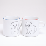 A pair of white Ennui porcelain mugs, made by Angle Ceramic in Japan and on show at NiMi Projects UK. On the left the mug features an illustration of a fluffy puppy and the words "Bow wow," on the right the mug features a cat and the word "Meow"