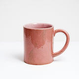 Side view of a large pink glazed Japanese ceramic mug with a handle at an unusual angle to make it easier told and tilt. Hand made by Angle in Japan and available at NiMi Projects UK.