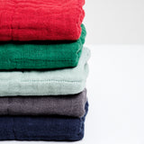 Stack of folded colourful Ban Inoue Japanese muslin kitchen dishcloths on a white background at NiMi Projects UK.