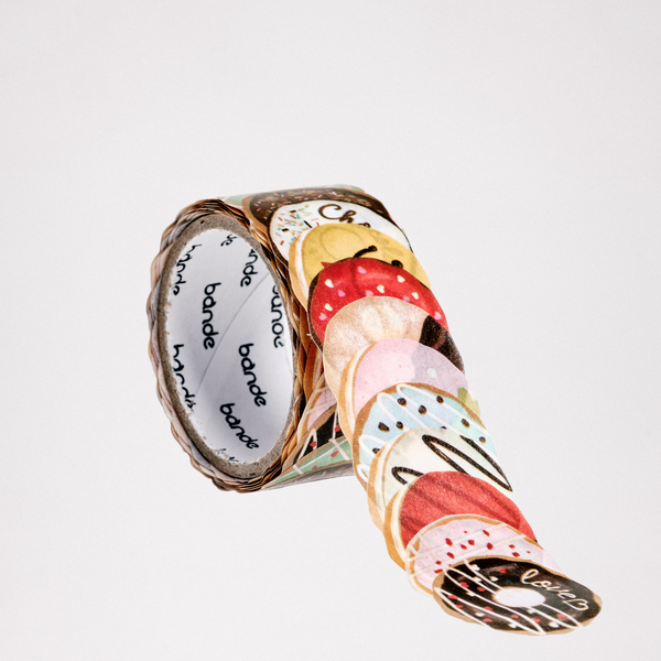 A roll of brightly coloured donut design Japanese washi paper stickers, made in Japan by Bande. Each sticker features a different iced ring donut and are individually cut. The stickers are layered slightly atop each other to create the strip for the roll. Available at NiMi Projects UK.