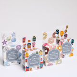 Four packages of Japanese washi paper tape stickers, each featuring a different graphic design — from left to right, seashells, houses, doughnuts and hot air balloons.