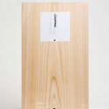 A large Hinoki Japanese cypress chopping board with a smooth, pale wood finish, shown from above with its white product label. Available at NiMi Projects UK.