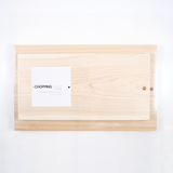 A small Hinoki Japanese cypress chopping board  laid on top of a large chopping booard, both with a smooth, pale wood finish, shown from above. Available at NiMi Projects UK.