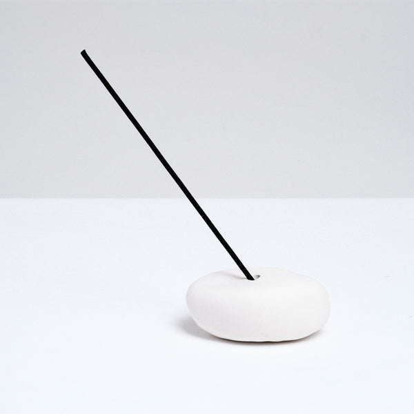 A medium-sized Maki Baxter ceramic pebble-shaped stick incense holder on show at NiMi Projects UK. The pebble is holding a stick of Japanese Daily incense by Trunk Design.