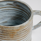 Detail of a mint and beige ribbed stoneware mugs by Maki Baxter. Available at NiMi Projects UK.