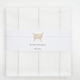 Top view of a white, folded Japanese fukin kitchen cloth, detailed with beige vertical stitched lines and wrapped in a white slip with a gold and white mizuhiki paper cord knot in a traditional awaji design. Available at NiMi Objects.