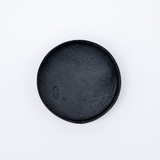 Ariel view of a small, round Rhythmos, up-cycled, skived split leather tray in navy blue. The tray has been molded into shape by Japanese leather artisans and is available at NiMi Projects UK.
