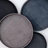 Ariel view of four round, up-cycled skived split leather trays in different shades of blue. Molded into shape by Japanese leather artisan Rhythmos and available at NiMi Projects UK.