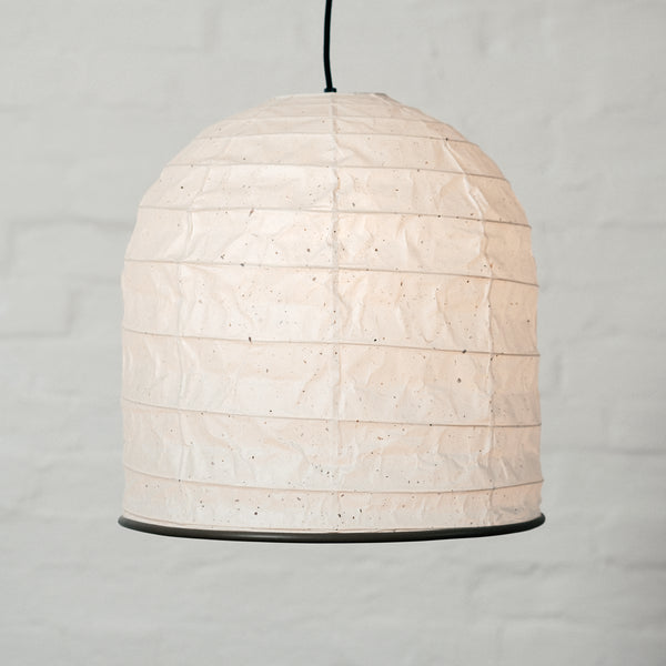 A white Saiko Design Yama Japanese  washi paper lampshade on show at NiMi Projects UK. Named after the Japanese word  for "mountain,"  its form is like that  of  a bell. The framework holding out its shape is made using traditional Japanese  chochin lantern techniques.