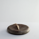 Side view of a round Yakushima wild cherry wood pedestal plate finished with washi paper and urushi lacquer with a dusting of tin powder. Made by Japanese artisan Solmu Puut and on show at NiMi Projects UK.