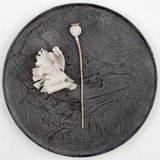 Top view of a large round wild cherry wood plate, textured with layers of washi paper and deep brown lacquer. Made in Japan from wood sourced from thinning projects in Yakushima and hand crafted by wood artisans Solmu Puut. On display with white dried flowers at NiMi Projects UK.