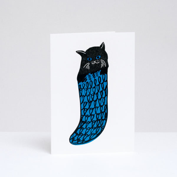 A Takako Copeland illustrated and letterpress printed Christmas cards, available at NiMi Projects UK, featuring a black cats in a blue knitted stockings. 
