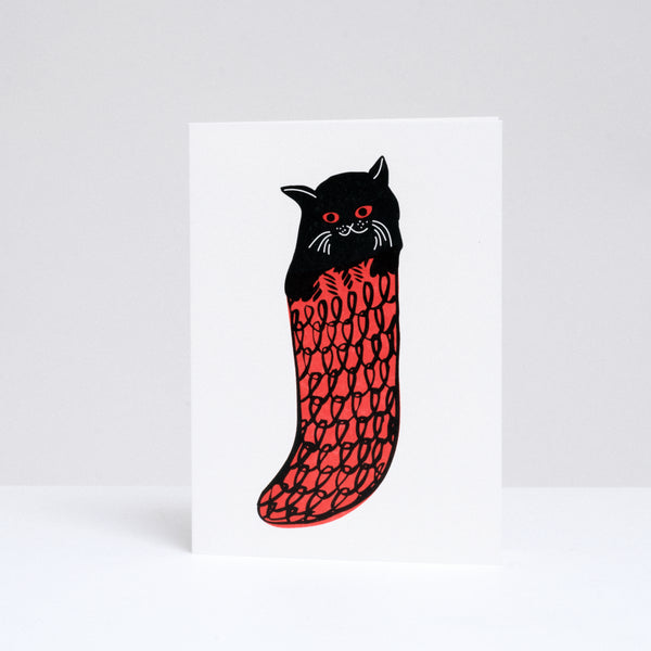 A Takako Copeland illustrated and letterpress printed Christmas cards, available at NiMi Projects UK, featuring a black cats in a red knitted stockings. 