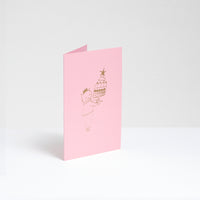 A standing pink greeting card, designed by Takako Copeland, featuring a gold foil line drawing illustration of a cat in a party crown and sweater holding a large trifle on a platter. Available at NiMi Projects UK. 