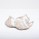 A vintage Japanese ceramic dish in the shape of a maple leaf glazed in natural off-white or light beige and speckled with brown flecks and featuring pattern of dripped milky white glaze.. 