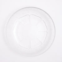 Top view of a small vintage Japanese glass plate, featuring a central flower motif with petals textured with lines that match the plates border. Available at NiMi Projects.