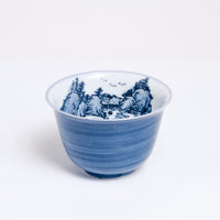 A vintage white porcelain Japanese teacup with a hand-painted blue exterior and a blue mountainscape inside. Available at NiMi Projects UK.