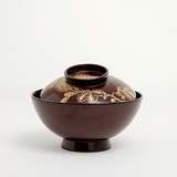 Sidevew of a vintage Japanese lacuerware bowl, showing a gilt gold, hand-painted design of chrysanthemums across the lid. On show at NiMi Projects UK.