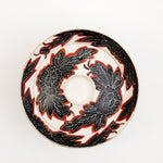 Top view of a white vintage, Japanese porcelain, decorative lidded donburi bowl, showing a bold pattern of peonies in black with white detailing and brick red borders. On show at NiMi Projects UK.
