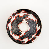 Top view of a white vintage, Japanese porcelain, decorative lidded donburi bowl, showing a bold pattern of peonies in black with white detailing and brick red borders. On show at NiMi Projects UK.