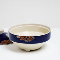 Top view of a Japanese, vintage, round porcelain bowl showing a deep blue glaze band along its side,  and a cloud-shaped patterned motif in red and gold.