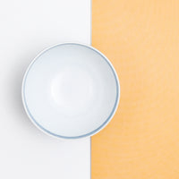 Top view of a vintage Japanese porcelain tea cup against a bi-colour background ow white on the left and yellow on the right.