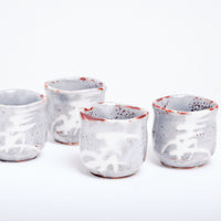 Four large vintage Japanese tea cups with off-white, greyish glaze with details of brown speckles. On their outsides are patterns of brushstrokes resembling the kanji for lucky or wheat.