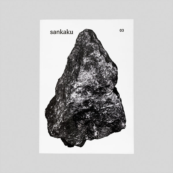 The white cover of the Sankaku Vol. 3: GODS book, featuring a large photographic image of a triangular, naturally formed dark grey rock. Published by sankaku and available at NiMi Projects UK. Photo by Sankaku.