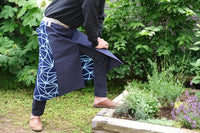  A contemporary take on the traditional maekake Japanese apron with a blue sailcloth canvas front panel, two pockets, patterned tenugui cotton and a sanada himo double wrap woven waist cord. Made in Japan, available at NiMi Projects UK.