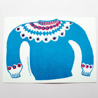 Takako Copeland’s Icelandic Sweater letterpress-printed card featuring an illustration of a bright blue and red patterned sweater that spreads across both sides of the card.