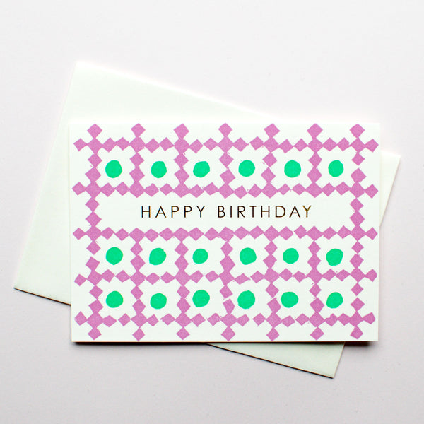 Takako Copeland’s letterpress-printed Birthday Card featuring a textile-like pattern of purple diamond bordered squares, each with green circle inside. Central to the design are the words “Happy Birthday” in gold.