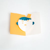 The Boy Face Popup Card, designed by Yasuyuki Wada, features a green-haired lad wearing a yellow hat, against a yellow background. Open it up and his eyes and mouth move! This card comes as a DIY kit of pre-cut paper, made in Japan and available in the UK at NiMi Projects.