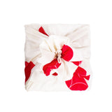 A Musubi Seven Treasures furoshiki Japanese wrapping cloth with large red circles on a white background,wrapped around a square gift.