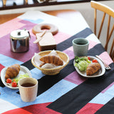 Masaru Suzuki's Stripe Horse furoshiki, designed for Musubi, used as a tablecloth on a wooden table set for lunch.