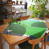 Masaru Suzuki's green and blue Water Bird furoshiki, designed for Musubi, laid out on a wooden table as a tablecloth.