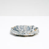 A side view of a NiMi Projects’ Buoy recycled plastic polygon-shaped soap dish in mottled grey and white, made of waste marine plastic collected from beaches in Japan.Edit