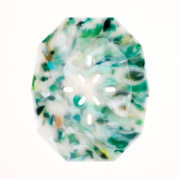 A birds-eye view of a white and green recycled marine waste plastic polygon-shaped soap dish, made by Buoy in Japan and available at NiMi Projects UK.