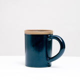 A NiMi Projects' Japanese Mino-yaki ceramic Straight Mug, glazed in navy blue. The mugs hand is extra wide and rounded, while its lip is left unglazed, revealing the natural texture and color of the clay.