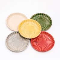 Five NiMi Projects' Japanese porcelain Mino-yaki Hana Akari radially fluted chrysanthemum dishes in different colors. Clockwise from top left — white, green, red, grey and yellow in the center.
