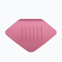 A sakura pink colored, stainless-steel Irogami kitchen hand grater, square in shape with a curved corner, designed and made in Japan and available at NiMi Projects UK.
