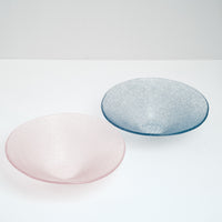 Two large artisanal Shari Shari conical glass bowls — one in pink and the other in blue-purple, made in Japan by Saburo and available at NiMi Projects. The glass features tiny bubbles, giving the bowls a soft frosted effect.
