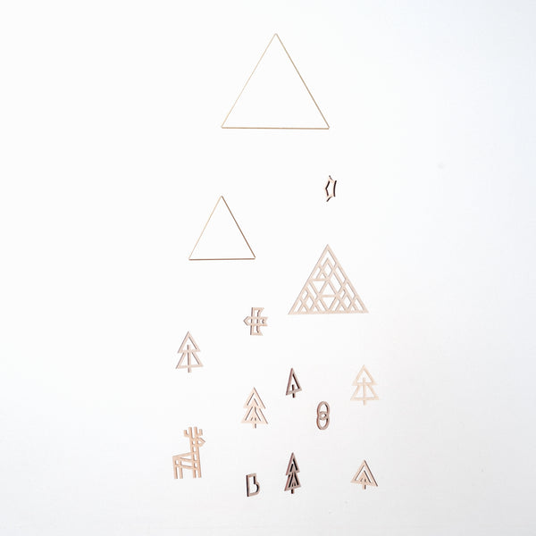 Forest mobile, designed by Sukima and made in Japan, featuring two brass wire triangles, one wood triangle and wooden cutouts of a bird, deer, snowman, stocking and trees. Available at NiMi Projects UK