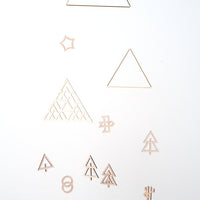Detail of a wooden forest mobile, showing tiny cutout trees, a bird and star, hanging from brass triangles - designed in Japan by Sukima  and available at NiMi Projects UK