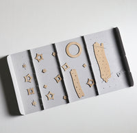 A star mobile in natural wood, packaged in a fold-out paper box, specially designed to keep it parts tidy. Included are 2 milky way parts, one circular moon and 14 different shaped stars, designed by Sukima in Japan
