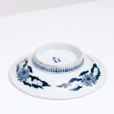 The bottom of a 1940s vintage Japanese white Arita Porcelain plate, featuring a design of blue lotus flowers and leaves and small stripes on the base. Available at NiMi Projects UK