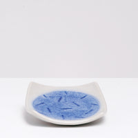 A NiMi Projects  UK vintage square Japanese porcelain small dish in white, featuring a blue glaze central circle design with a pattern of small dark blue lines.