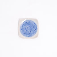 A NiMi Projects UK vintage square Japanese porcelain small dish in white, featuring a blue glaze central circle design with a pattern of small dark blue lines.