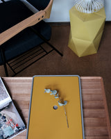 A detail of Atelier Yocto's premium Tray Table, hand crafted in Japan in Japanese Walnut wood, along with Yocto's tray in light gray, and the lid in a fetching shade of mustard. Available at NiMi Projects, UK.